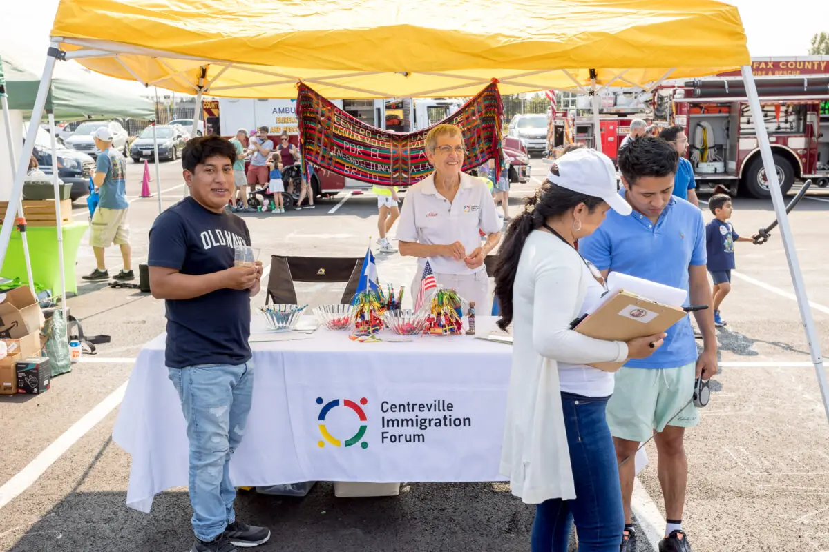 The Centreville Immigration Forum exhibitor booth showing their display and attendees talking to booth staff.