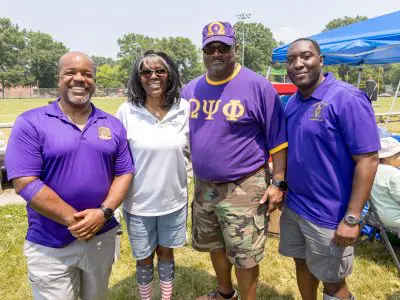 Four people at Gum Springs Community Day side by side smiling at camera.