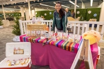 Woman standing behind a table with a pink tablecloth and a white railing