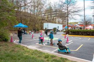 Children playing in a parking lot with scooters and bikes