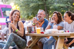 A group of people laughing at a table in an outdoor setting
