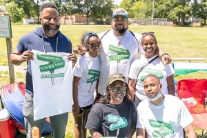 A group of people posing for a photo in a park, with a focus on community and social interaction