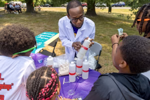 Man in white lab coat teaching children science