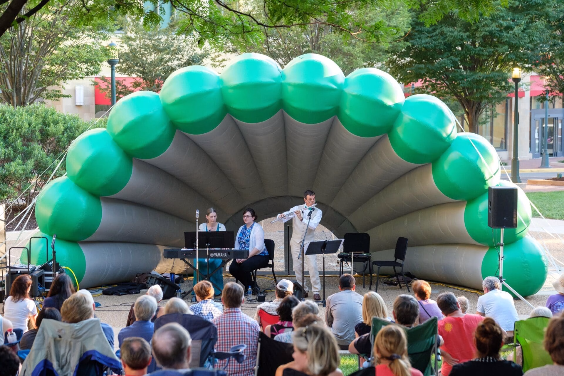 Musicians performing on an outdoor stage with a large inflatable archway