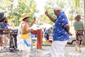 An older couple dancing in a park on a sunny day.