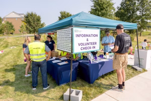 Group of volunteers standing at a table with a sign that says 'Information & Volunteer Check-In'