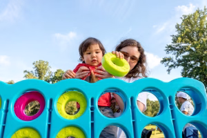 A woman and a young child playing with a large, colorful plastic toy in a park