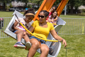 A woman and two children enjoy a ride on a swing in a park.