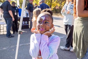A young girl with unicorn face paint at an outdoor event