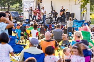 A crowd of people watching a band perform on stage in a park