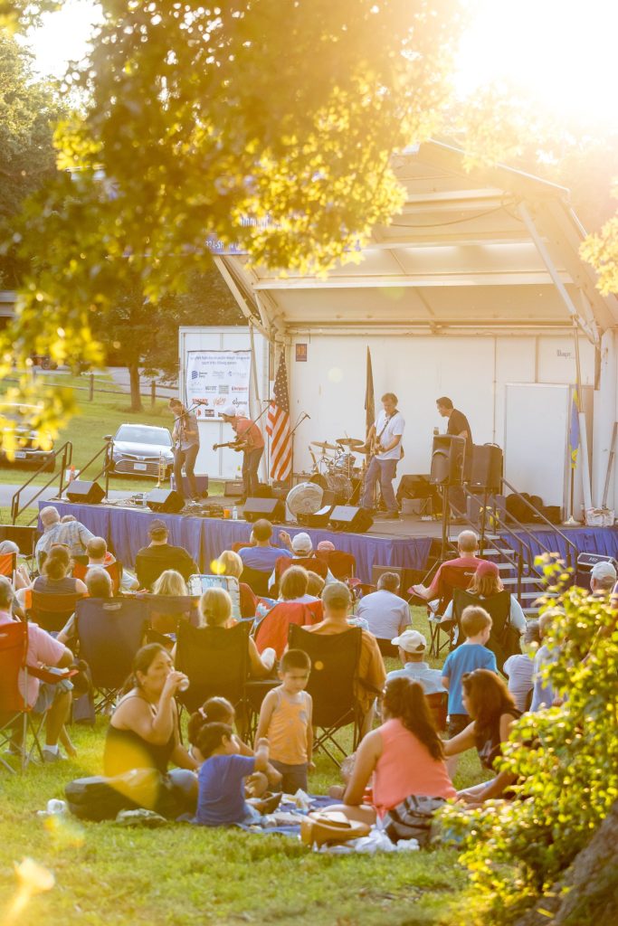 A lively outdoor concert in a park, with people enjoying the music and the sun.