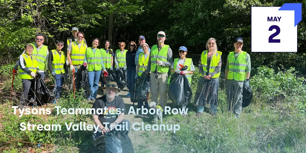 A group of people wearing yellow vests and holding trash bags in a wooded area.