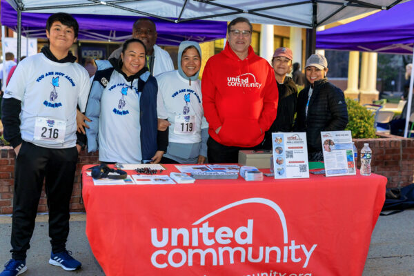 Picture of participants poisng with an exhibitor at the table for United Community