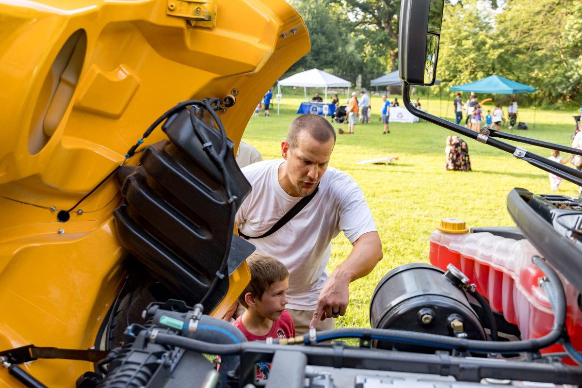 Man and boy looking at the open hood of a FCPS electric bus at the Celebrate Fairfax Kids event on July 19, 2023